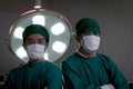 Two professional surgeon doctor standing under bright light, using surgical equipment to do surgery at hospital operating room. Royalty Free Stock Photo