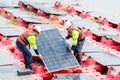 Two professional technician workers hold and carry solar cell panel to set up or install to the base over area of water reservoir