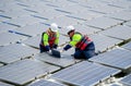 Two professional technician workers sit and work together using laptop in area of solar cell panel system in concept of green Royalty Free Stock Photo