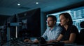 Two professionals analyzing data on computer screens in a modern control room environment Royalty Free Stock Photo