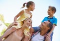 Two proud parents. A cropped shot of two happy parents carrying their young kids on their shoulders outdoors. Royalty Free Stock Photo