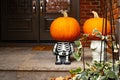 Two pumpkin-heads on small skeleton Halloween cute sculpture standing at the front doors outside of the fancy home