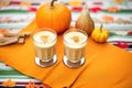 two pumpkin spice lattes in togo cups on a fallcolored tablecloth
