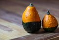 Two Pumpkins, Orange and Green, different seizures, on a Table, like two Friends