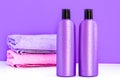 Two purple cosmetic bottles and two towels on a lilac background Royalty Free Stock Photo