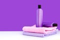 Two purple cosmetic bottles on two towels on a lilac background. Spa concept Royalty Free Stock Photo