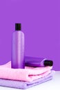 Two purple cosmetic bottles on two towels on a lilac background. Spa concept Royalty Free Stock Photo