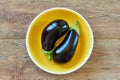 Two purple eggplants on a yellow plate on a wooden tabletop Royalty Free Stock Photo