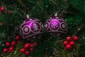 Two purple festive balloons with the image of a Christmas tree and snowflakes hanging on artificial branches of a spruce Royalty Free Stock Photo