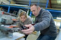 Two qualified workers working on machine in factory