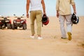 Two racers hold helmets near atvs in desert Royalty Free Stock Photo