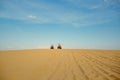 Two racers riding on atv in desert, afar view Royalty Free Stock Photo