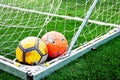 Two ragged shabby soccer balls in the corner of the goal. Royalty Free Stock Photo