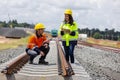 Two railway engineers inspect concrete sleepers and rail alignment using a tablet. Royalty Free Stock Photo