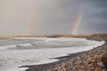 Two rainbows in the sky over a beach.