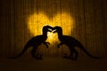 Two raptors - dinosaurs - in front of a glowing heart.