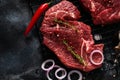 Two Raw beef steak with spices, onions and chili on dark slate or concrete background. Royalty Free Stock Photo