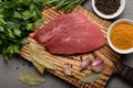 Two raw beef steaks with spices on a cutting board on black background