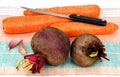 Two raw beets, three carrots and a knife.