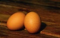 Two brown chicken eggs on the old teak table, in shallow focus