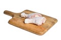 Two raw chicken legs with skin lying on a wooden cutting board. Fresh uncooked meat of poultry isolated on white background Royalty Free Stock Photo