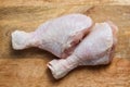 Two raw chicken legs with skin lying on a wooden cutting board. Fresh uncooked meat of poultry isolated on white background. Top Royalty Free Stock Photo
