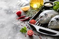 Two raw dorado fish with spices, lemon and parsley in a black grill pan on a white concrete background. Copy space Royalty Free Stock Photo