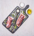 Two raw duck breast on a cutting board with a wooden spoon, wild rice, oil and salt wooden rustic background top view close up Royalty Free Stock Photo