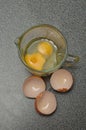 Two raw eggs in a measuring cup with egg shells Royalty Free Stock Photo