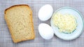 Two raw eggs next to a cut piece of bread and grated cheese Royalty Free Stock Photo