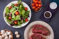 Two raw filet steaks with a green salad, cherry tomatoes