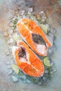 Two raw fresh salmon or trout steaks on ice, rich in omega-3 oil, with lime, thyme and olive oil on a blue rusty background. Royalty Free Stock Photo