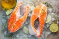 Two raw fresh salmon or trout steaks on ice, rich in omega-3 oil, with lime, thyme and olive oil on a blue rusty background. Royalty Free Stock Photo