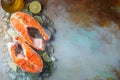 Two raw fresh salmon or trout steaks on ice, rich in omega-3 oil, with lime, thyme and olive oil on a blue rusty background. Royalty Free Stock Photo