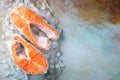 Two raw fresh salmon or trout steaks on ice, rich in omega-3 oil, with lime, thyme and olive oil on a blue rusty background. Royalty Free Stock Photo