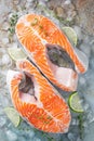 Two raw fresh salmon or trout steaks on ice, rich in omega-3 oil, with lime, thyme and olive oil on a blue rusty background. Royalty Free Stock Photo