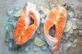 Two raw fresh salmon or trout steaks on ice, rich in omega-3 oil, with lime, thyme and olive oil on a blue rusty background. Royalty Free Stock Photo