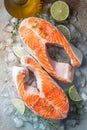 Two raw fresh salmon or trout steaks on ice, rich in omega-3 oil, with lime, thyme and olive oil on a blue rusty background. Royalty Free Stock Photo