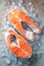 Two raw fresh salmon or trout steaks on ice, rich in omega-3 oil, with lime, thyme and olive oil on a blue rusty Royalty Free Stock Photo