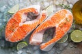 Two raw fresh salmon or trout steaks on ice, rich in omega-3 oil, with lime, thyme and olive oil on a blue rusty Royalty Free Stock Photo