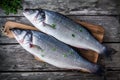 Two raw fresh sea bass on a cutting board with thyme