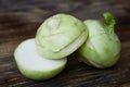 Two raw kohlrabies on the rustic wooden table, one is cut