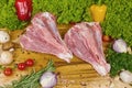 Two raw legs of turkey divided on a wooden board with cherry tomatoes, lettuce, garlic, chilli, rosemary, onion, ready Royalty Free Stock Photo