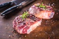 Two raw pieces beef shank on wooden butcher board with fork and