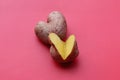 Two raw potatoes in the shape of a heart together on a red background, one potato is cut, an old heart. Potato love