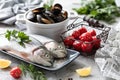 Two raw rainbow trout fish on a plate, greens and fresh vegetables for preparing healthy and tasty food. White pan with mussels on Royalty Free Stock Photo