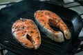 Two raw salmon steaks with spices and herbs on a grill pan. Close up bbq grilled salmon steaks on black cast-iron ribbed frying p Royalty Free Stock Photo