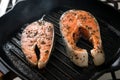 Two raw salmon steaks with spices and herbs on a grill pan. Close up bbq grilled salmon steaks on black cast-iron ribbed frying p Royalty Free Stock Photo