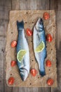 Two raw seabass fish with a lemon slice and cherry tomatoes on w Royalty Free Stock Photo