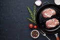Two raw steaks on pan with rosemary and pepper on dark stone background. Royalty Free Stock Photo